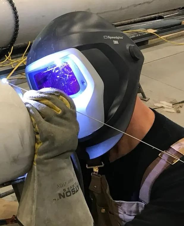 Person welding with helmet and gloves